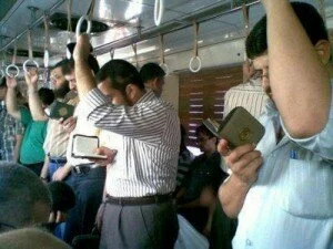 Three people reading Quran in train